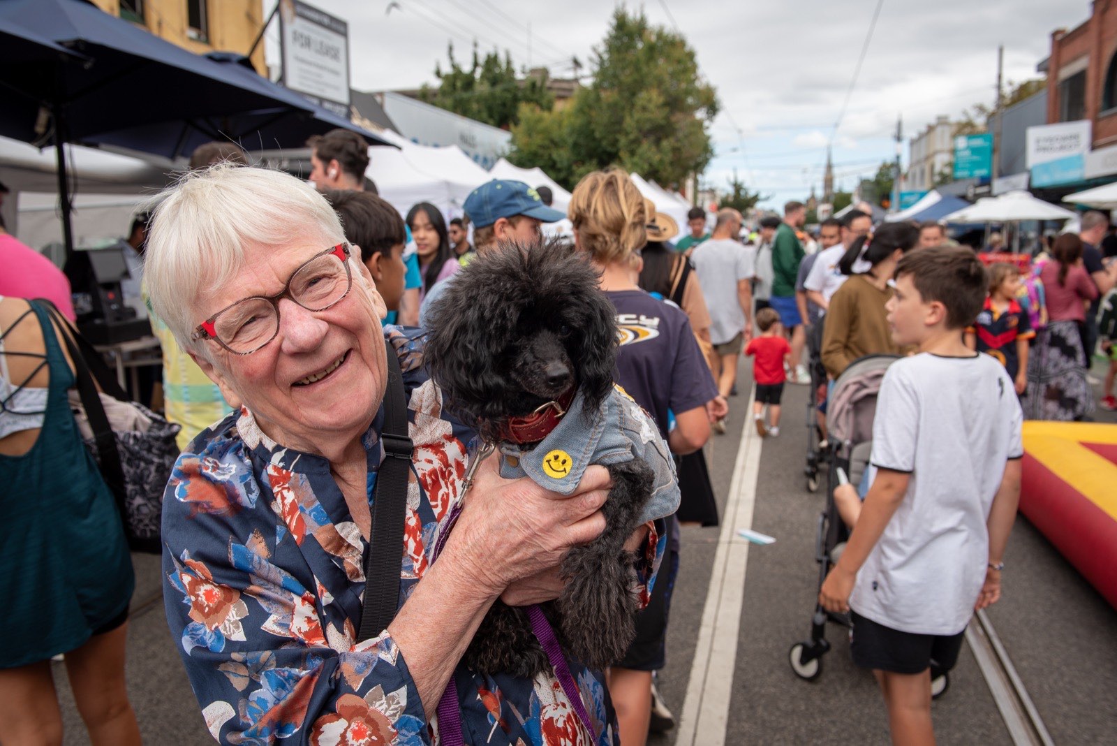 A festival-goer cuddling a small dog in the crowd