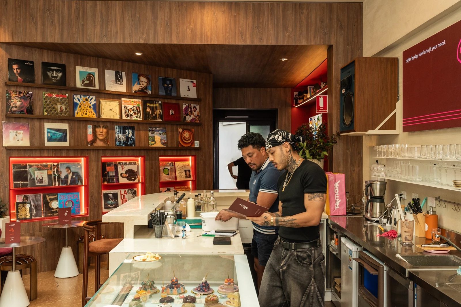 Two customers browsing the menu at the counter of Sabi Sounds, surrounded by shelves of records