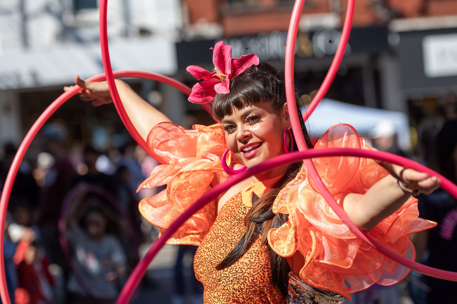 A street performer in orange twirling pink hoops