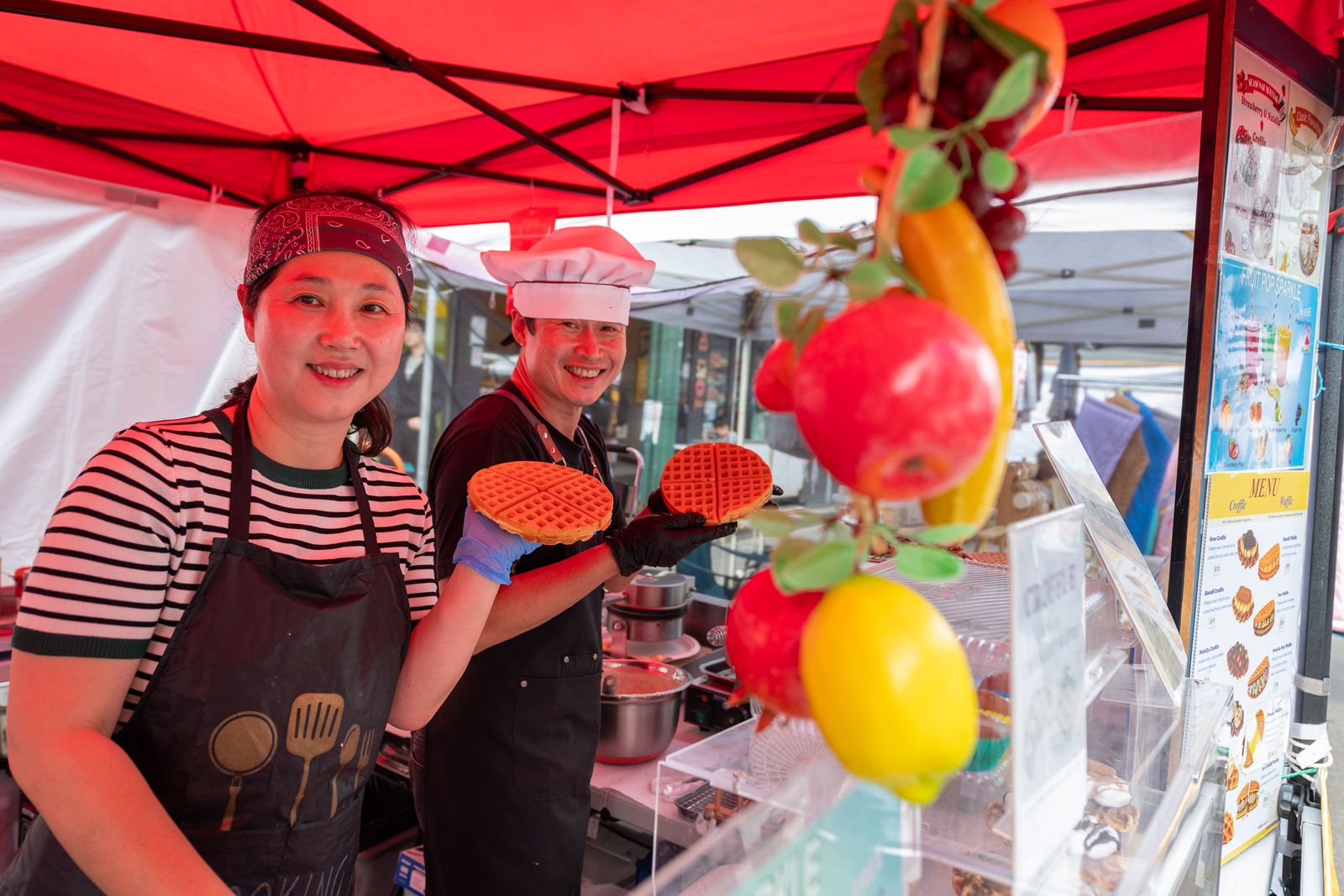 Smiling stallholders serving waffles at their festival stand