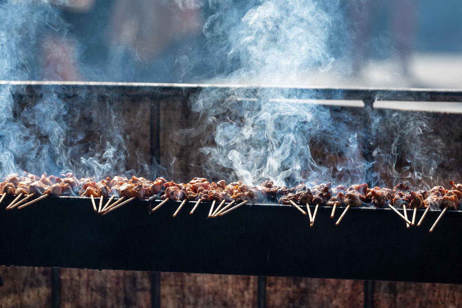 Satay skewers smoking on a charcoal grill