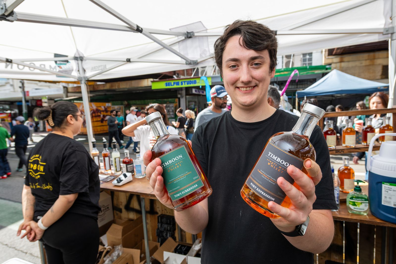 A stallholder showing off bottles at a distillery stand